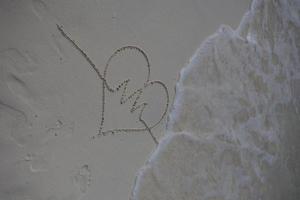 corazones dibujados en la arena de una playa foto