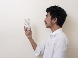 hombre que sostiene la bombilla de ahorro de energía para la lámpara foto