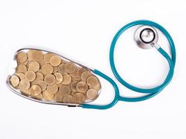 Medical stethoscope and coins stack isolated on white background. Medical insurance concept. photo