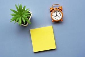 Adhesive Note with potted plant and alarm clock set at 8 o'clock. Copy space. photo