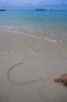 corazones dibujados en la arena de una playa foto