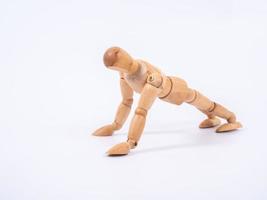 Small wooden dummy during push ups on white background photo
