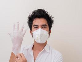 Confident man surgeon in medical mask on face wearing protective sterile glove on hand photo