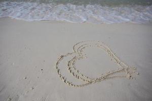 corazones dibujados en la arena de una playa foto