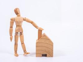 Man leaned against the model of a house isolated on white background. Concept with a wooden puppet photo