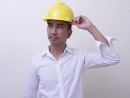 engineer with hands crossed wearing yellow helmet on white background photo