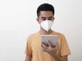 Man with digital tablet  wears surgical mask to protect from virus photo