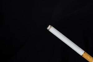 Burning cigarette with smoke on black background photo