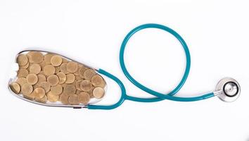 Medical stethoscope and coins stack isolated on white background. Medical insurance concept. photo