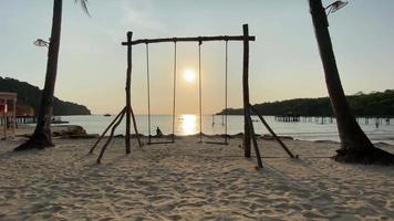 Beach swing and watching ocean waves. Carefree summer moment at ocean beach. video