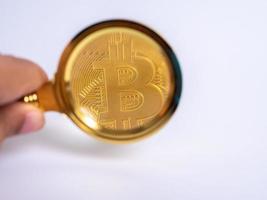 Golden bitcoin magnifying glass on a blurred background of coins photo