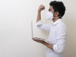 Business man in medical face mask works on laptop at home photo