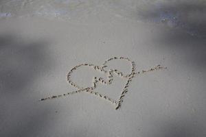 corazones dibujados en la arena de una playa foto