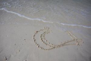 corazones dibujados en la arena de una playa foto