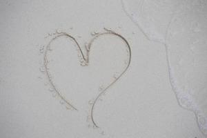 corazones dibujados en la arena de una playa foto