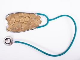 Medical stethoscope and coins stack isolated on white background. Medical insurance concept. photo