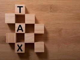 Tax with wooden alphabet blocks, on plank wooden background with copy space photo