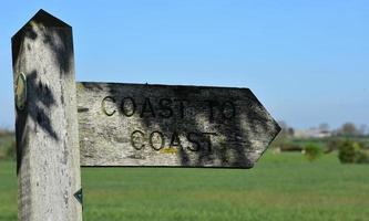 Wood Sign Post with a Lush Landscape Behind It photo