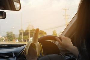 Lady eating banana while driving car dangerously photo