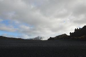 vistas a la montaña desde la playa de arena negra en islandia foto