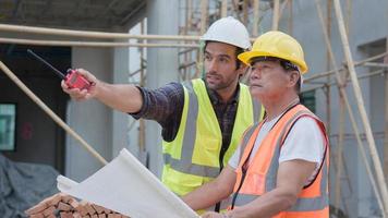 ingeniero civil o arquitecto profesional masculino, inspector con contratista, capataz o trabajador. mientras mira el plan de planos, inspecciona, discute el proyecto de construcción de reuniones y señala el sitio de construcción. foto