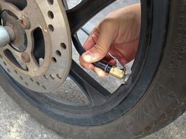 Asian man inflates old motorcycle wheels for road safety photo