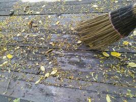 broom and autumn leaves on wooden ground photo