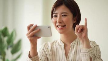 una mujer que estudia las letras de los dedos del lenguaje de señas japonés en su teléfono inteligente