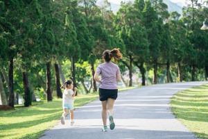 Mother and daughter runners are jogging in the park. Evening. Family activities . Mother and son in sportswear are running and having fun. photo