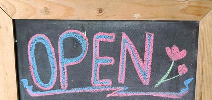 open sign written in colorful chalk on a wooden board. photo