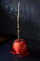 Halloween candy apple with gold stick on dark background photo
