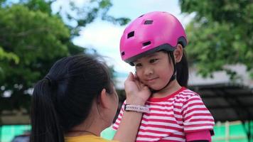 Loving mother helping her daughter to playing roller skate in the park. Mother encourages daughter to practice roller skating. Exciting outdoor activities for kids video