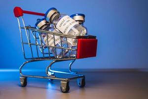 COVID-19 booster vaccine vials in shopping cart. Medicine and health care concept photo