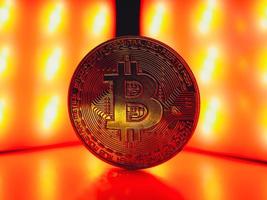 una moneda con símbolo de bitcoin en luz roja. concepto de una crisis del mercado de criptomonedas. foto