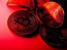 Twisted coins with bitcoin symbol on red light. Concept of a cryptocurrency market crisis. photo