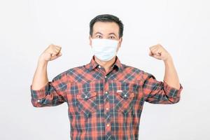 Passed bad situation concept, Asian man wearing protective face mask in action of glad, victory or very happy isolated on grey photo
