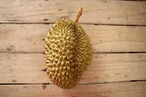 Durian, a large fruit laying on a brown plank floor. It is a fruit of Thailand that is abundant in summer. photo