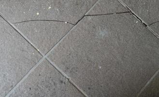 Broken cracked damaged floor tiles surface in need of repair old texture background. photo