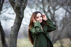 Image of young beautiful woman wearing rain jacket in cold weather. Thinker european girl in spring nature. photo