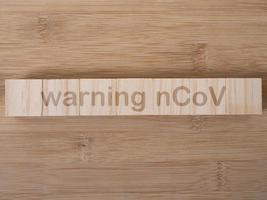 palabra de advertencia ncov escrita en bloque de madera. texto de advertencia ncov en la mesa de madera para su diseño, vista superior del concepto de coronavirus foto