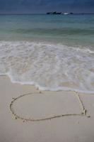 corazones dibujados en la arena de una playa foto