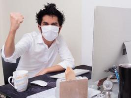 Young Asian boy wearing face mask working on laptop computer during coronavirus pandemic photo