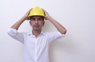 ingeniero con las manos cruzadas usando casco amarillo sobre fondo blanco foto