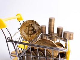 Pay crypto currency the supermarket cart is filled with gold coins of bitcoin on a white background. Copy space photo