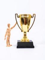 Wooden toy figure and golden trophy cup on white background photo