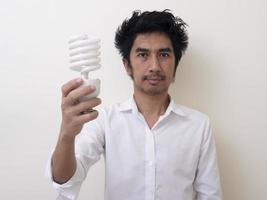 hombre que sostiene la bombilla de ahorro de energía para la lámpara foto