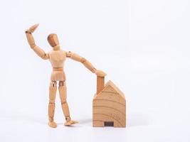 Man leaned against the model of a house isolated on white background. Concept with a wooden puppet photo