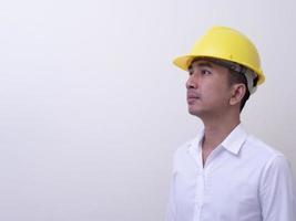 engineer with hands crossed wearing yellow helmet on white background photo