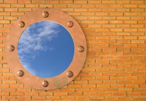 cielo azul en el agujero de la pared vieja, marco de ladrillo foto