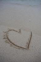 corazones dibujados en la arena de una playa foto